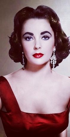 an old photo of a woman in a red dress with big earrings on her head