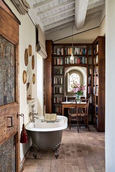 a bath tub sitting inside of a bathroom next to a book shelf filled with books