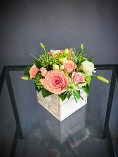 a wooden box filled with flowers on top of a glass table