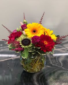 a vase filled with lots of different colored flowers