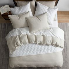 a bed with white and beige pillows on top of it