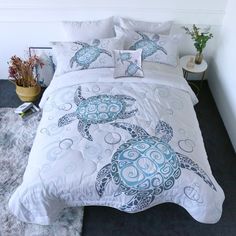 a bed with two sea turtles on the comforter and pillow cases, along with decorative throw pillows