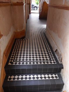 black and white tiled stairs leading up to a car parked in the garage behind them