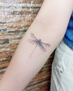 a small dragonfly tattoo on the arm