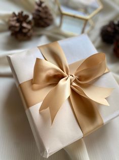 a present wrapped in white paper with a gold bow