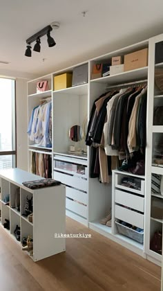 an organized closet with clothes, shoes and other items on the shelves in front of a large window