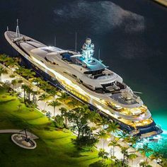 an aerial view of a yacht docked in the water at night with its lights on