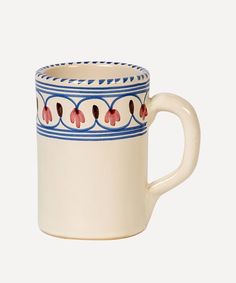 a white coffee cup with blue and red designs on the outside, sitting in front of a white background