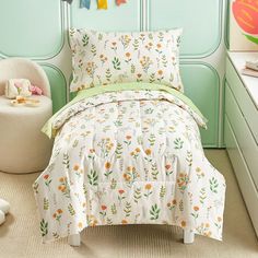 a child's bedroom with green walls and white bedding, including an orange flowered comforter