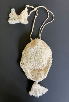 Vintage crocheted bag with tassels. The vintage bag is creamy white color with a intricate elongated design, gathered together at the bottom with one of the tassels. The cloth lining is hand stitched at the top just under the crocheted shell loops for the drawstrings on the vintage bag. This vintage crocheted bag is 6 inches long, not counting the tassel and 4 1/2 inches wide. Vintage Natural Crochet Bag, Vintage White Crochet Bag For Summer, Vintage Beige Crochet Bags, Beige Vintage Crochet Bags, Cream Woven Crochet Pouch Bag, Vintage Handmade Cream Crochet Bag, Vintage Cream Handmade Crochet Bag, Vintage Cream Crochet Handmade Bag, White Bohemian Crochet Pouch Bag