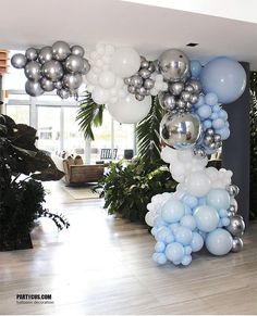 a bunch of balloons that are on the ground in front of some plants and trees