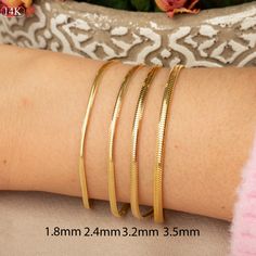 Our 14K Gold Snake Chain Bracelet is the epitome of sleek design and modern luxury. This handcrafted piece, with its distinctive flat snake chain, offers a smooth and comfortable fit, making it perfect for daily wear or special occasions. The high-quality 14K gold construction not only imparts lasting durability but also an undeniably elegant aesthetic. Available in various widths and lengths, this bracelet can be personalized to your exact preference for a snug or more relaxed fit. Key Features Tarnish Resistant Snake Chain Bracelet, Gold Snake Chain Bracelet, Modern Gold Snake Chain Bracelet, Elegant 14k Gold Snake Chain Bracelet, Elegant Snake-shaped Chain Bracelet Gift, Everyday Gold Snake Chain Bracelet, Tarnish Resistant, Elegant Yellow Gold Snake Bracelets, Elegant Gold Snake-shaped Bracelet, Flat Snake Chain