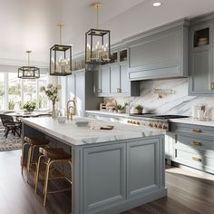 a large kitchen with gray cabinets and marble counter tops, gold pendants hanging from the ceiling