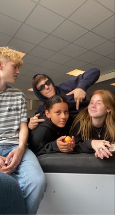 four young people are sitting together and posing for the camera