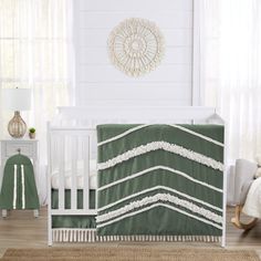 a white crib with a green and white bedding set on top of it