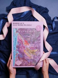 a person holding up a book that is covered in pink and blue fabric