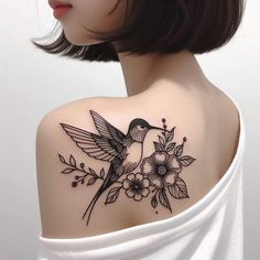 a woman's shoulder with a bird and flowers tattoo on her upper arm,