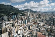 an aerial view of a large city with mountains in the backgrouund and clouds in the sky