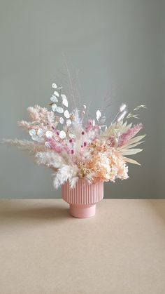 a pink vase filled with lots of white and pink flowers on top of a table