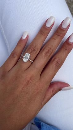 a woman's hand with white manicured nails and a diamond ring