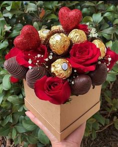 someone is holding a box with chocolates and roses in it