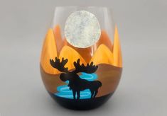 a glass with an image of a moose in the water on it's side