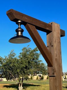 a lamp hanging from the side of a wooden structure in a park with grass and trees