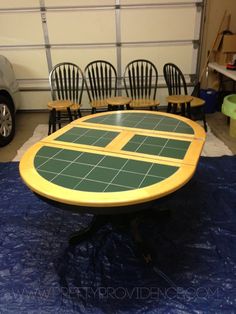 a table that has been painted yellow and green with four chairs in front of it