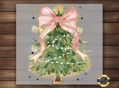 a christmas tree with pink bow and lights on it is displayed in front of a wooden wall