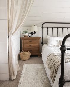 a bedroom with a bed, dresser and rug in the corner next to a window