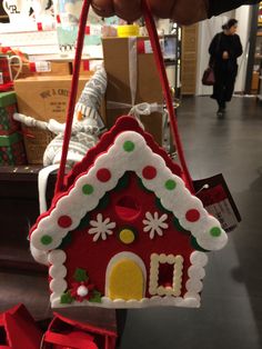 a hand holding a red and white house ornament