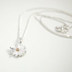 A beautifully designed 925 Sterling Silver Daisy Pendant with a Gold Plate stamen in the centre. The daisy is the April birth flower but also represents innocence, purity and new beginnings, which is why they are often gifted to new mothers or as gift for children.Choose which chain length you would prefer from the drop down menu. A lovely gift for family or friends or maybe something nice for yourself.Your purchase will arrive in a organza gift pouch but if you would like a luxury ribboned box, Dainty Daisy Sterling Silver Jewelry, Silver Daisy Jewelry Gift, Silver Daisy Jewelry For Gift, White Gold Sterling Silver Flower Necklace, Dainty Daisy Silver Jewelry, Mother's Day Sterling Silver Flower Necklace, Sterling Silver Daisy Jewelry With Flower Charm, Sterling Silver Daisy Flower Charm Jewelry, Delicate Sterling Silver Birth Flower Necklace