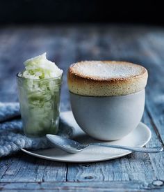 a cup and saucer sitting on top of a wooden table next to a spoon