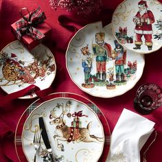 three plates with christmas decorations on them sitting next to a red table cloth and silverware