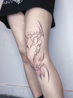 a woman's leg with a tattoo on it, showing her legs and thighs