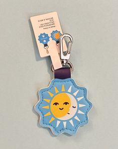 a blue and yellow keychain with a sun and moon on it's side