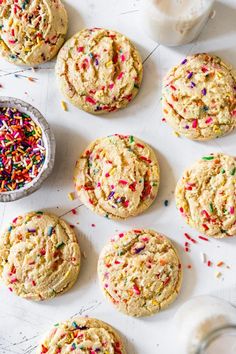 sprinkled cookies are arranged on a baking sheet and next to a bowl of sprinkles