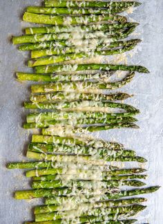 asparagus with parmesan cheese on top, sitting on a baking sheet