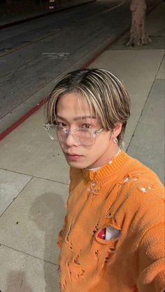 a young man wearing glasses and an orange sweater