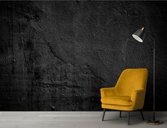 a yellow chair sitting in front of a black wall with a lamp on top of it