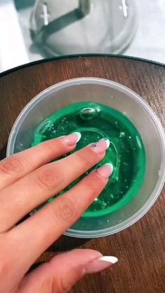 a woman's hand holding onto a green substance in a bowl