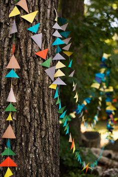 colorful paper birds hanging from the bark of a tree