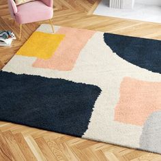 an area rug with various colors and shapes on the floor next to a pink chair