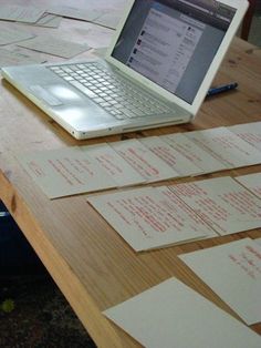 an open laptop computer sitting on top of a wooden table covered in papers and sticky notes