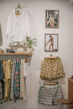 clothes are hanging up in a room with pictures on the wall and other items displayed