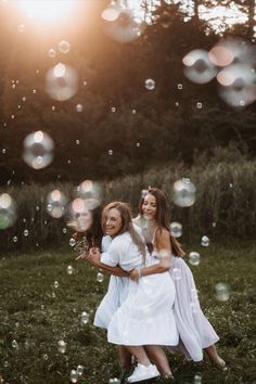 two girls in white dresses playing with bubbles