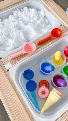 an ice cream tray with plastic spoons and colorful paints