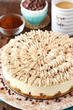 a cake sitting on top of a white plate next to bowls of chocolate chips and coffee