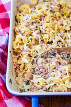 a casserole dish with ham and cheese in it on a red and white checkered tablecloth