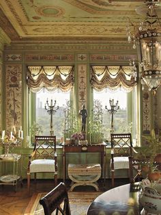 an ornately decorated dining room with chandelier and table in front of large windows